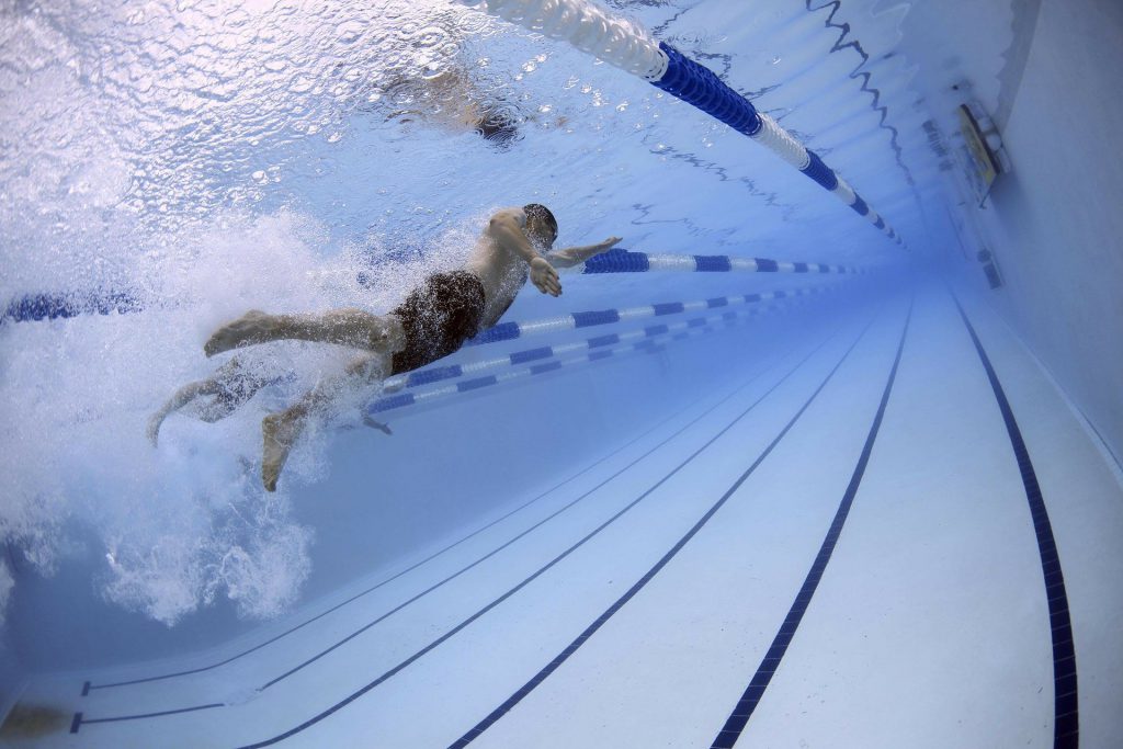 Pasek tła przedstawiający tor basenu i zanurzonego pod wodą mężczyznę.